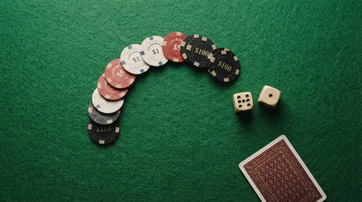 Vista cenital de fichas de casino y dados sobre una mesa de fieltro verde bajo luz suave.