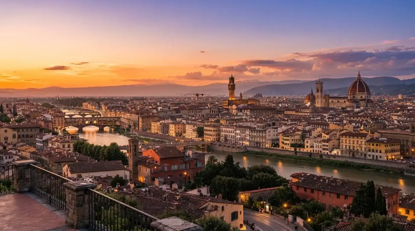 Vista panorámica de una ciudad europea al atardecer, con edificios iluminados y un cielo anaranjado de fondo.